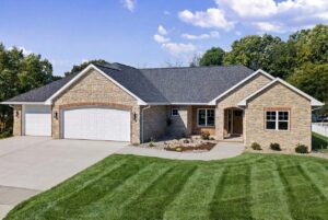 673 Black Earth Exterior. CertainTeed Landmark Driftwood Shingles. De Pere Ledgestone Blend (60% Buff + 40% Blue Vein). Old Carolina Brick Co. Old London #257 Brick. Soldier Course. Rowlocks. Arched Garage Doors. Masonry Archway at Front Entry.
