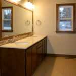 1800 Sonata Owner's Bathroom. Quartz Countertops with Tiled Backsplash and Wood-Framed Mirror. Ceramic Tile Floors.
