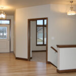 3424 Schubert Foyer + Stairs. Half Wal with Maple Cap. Natural Maple Hardwood Floors. Stained Maple Millwork.