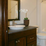3435 Schubert Main Bathroom Vanity. Stained Maple Flat Panel Custom Cabinets. Ceramic Tile Floors 12x24 Staggered Pattern. Vessel Sink. Granite Countertops.