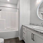 4976 Plum Bottom Rd Main Bathroom. White Painted Vanity Cabinet. Lighted Mirror. Vinyl Tile Floors. Tub/Shower Module with Curved Rod.