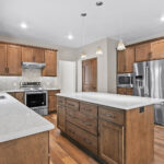 3597 E Hank Kitchen1 3597 E Hank Kitchen. Stone Countertops. Stained Maple Custom Cabinets. Under-Cabinet Range Hood. Built-In Microwave with Trim Kit. Herringbone Pattern Tiled Backsplash. Luxury Vinyl Plank Floors.