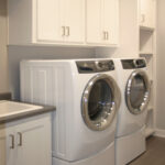 2411 Pristine Laundry. White Painted Cabinets. Utility Sink. Washer & Dryer on Pedestals