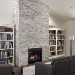 7730 Prestwick Living Room + Fireplace. Stacked natural stone fireplace surround to ceiling height. Cathedral ceiling. Luxury vinyl plank floors.