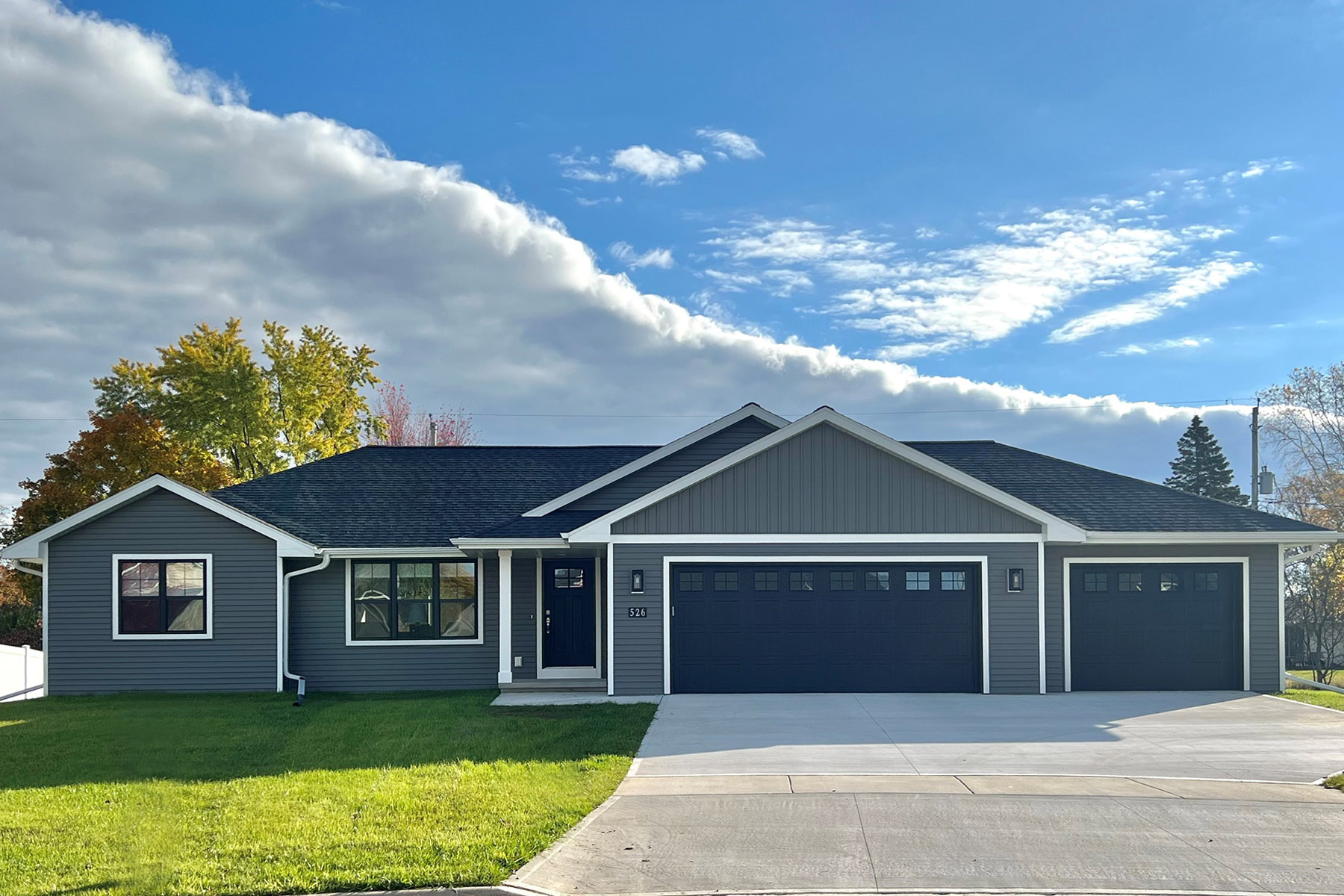 526 Rosemary Exterior. Black windows, black entry door, black overhead garage doors, white soffit/fascia, white exterior trim boards, Mitten "Yukon Gray" vinyl siding, CertainTeed Landmark "Moire Black" shingles.