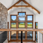 10510 Sugar Creek Great Room + Fireplace. Black interior windows, 2-story great room window wall, vinyl plank floors, ceiling beams, stone fireplace surround with lightweight concrete mantel.