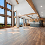 10510 Sugar Creek Great Room. Black interior windows, 2-story great room window wall, vinyl plank floors, ceiling beams, open riser glu-lam stairs with black cable railing.