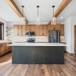 10510 Sugar Creek Kitchen. Custom maple cabinets, black island, quartz countertops, vinyl plank floors, ceiling beams, floating shelves, black interior windows over kitchen sink, under-cabinet lighting, tiled backsplash.