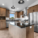 4749 Whitefish Bay Kitchen. Avery Grove Weathered Barn Oak Vinyl Plank Floors. Stained Maple Flat Panel Custom Cabinetry. Black Pearl Granite Countertops. SW7029 Agreeable Gray. Chimney Range Hood. Cathedral Ceiling.