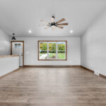4749 Whitefish Bay Living Room. Avery Grove Weathered Barn Oak Vinyl Plank Floors. SW7029 Agreeable Gray. Half Wall with Wood Cap at Stairwell. Cathedral Ceiling.