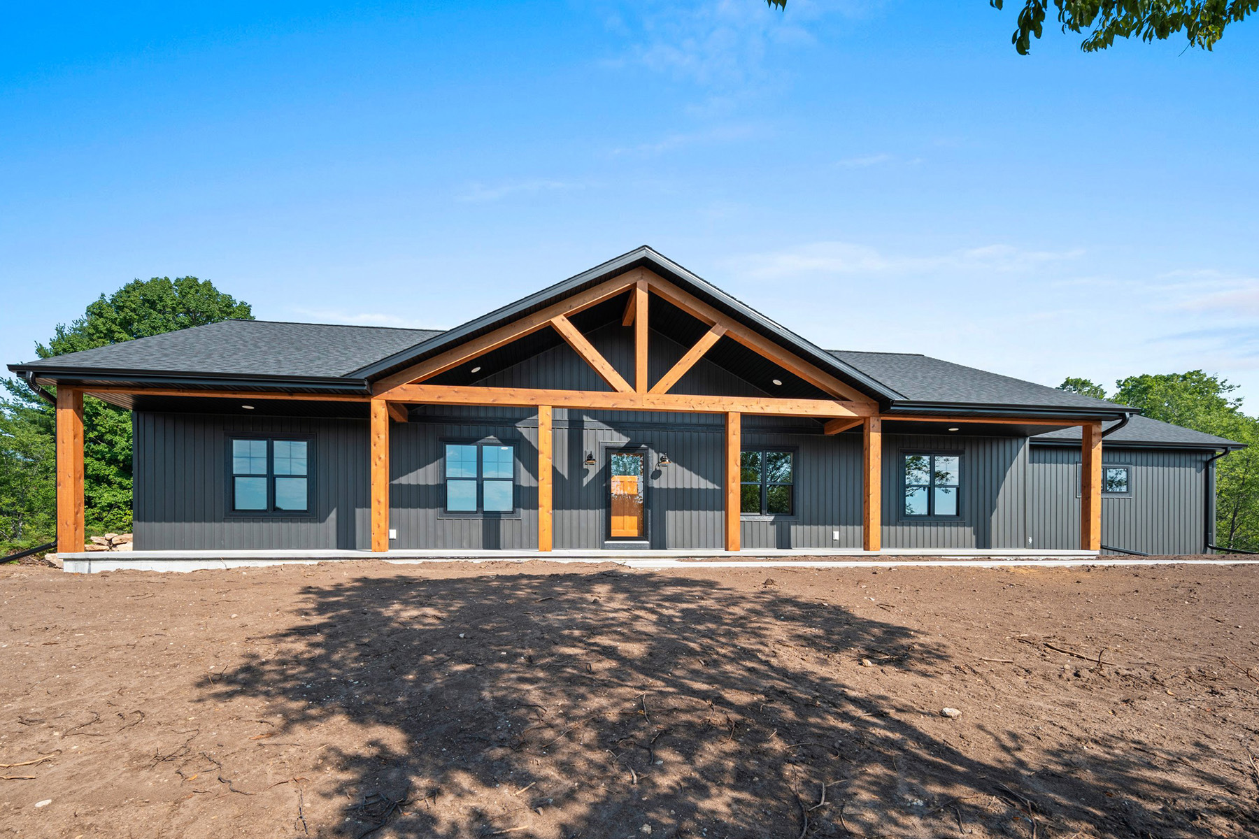 9185 Rasner Exterior. Covered Porch Cedar Timber Post & Beam. Black Vertical Board & Batten Siding Gentek Iron Ore. Black Windows.