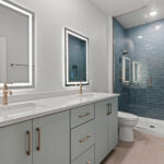 9185 Rasner Main Bathroom. SW 9137 Niebla Azul Painted Bathroom Vanity Cabinet Modern Slab Front Champagne Bronze Hardware Fixtures. Lighted LED Mirrors. Angora Teramoda Subway Tile Shower Walls with White Fiberglass Shower Base and Heavy 3/8" Glass Shower Enclosure.