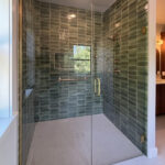 9185 Rasner Zero Entry Curbless ADA Accessible Tiled Shower. Gleeze Giada Green Subway Wall Tile. Angora Station Ivory Floor Tile. Tiled Shower Drain. Shampoo Niche. Heavy Glass Shower Enclosure. Champagne Bronze Hardware & Fixtures.