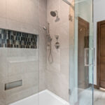 3409 Schubert Tiled Shower. Tiled Walls with Fiberglass Shower Base. Hand Shower with Slide Bar. Shampoo Niche. Foot Niche. Heavy Glass Shower Enclosure.