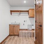 7120 Morrison Rd Laundry. Avery Grove "Weathered Barn Oak" Vinyl Plank Floors. Stained Maple Cabinetry and Woodwork. Raised Laundry Pedestal.