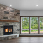 4673 Mill Rd Main Living Areas. Osborn Straftford II Wood-Burning Fireplace with Fond du Lac "Graphite Falls" Natural Thin Stone Veneer and Magra Hearth "Rustic Barnwood" Lightweight Concrete Mantel. Lone Star Spirit "Ballroom Rodeo" 9" Wide Vinyl Plank Flooring. Cathedral Ceiling. Raised Hearth Extension. Stained Maple Woodwork.