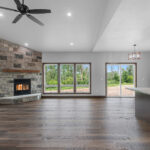 4673 Mill Rd Main Living Areas. Osborn Straftford II Wood-Burning Fireplace with Fond du Lac "Graphite Falls" Natural Thin Stone Veneer and Magra Hearth "Rustic Barnwood" Lightweight Concrete Mantel. Lone Star Spirit "Ballroom Rodeo" 9" Wide Vinyl Plank Flooring. Cathedral Ceiling. Raised Hearth Extension. Stained Maple Woodwork.