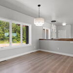 E1999 Hillside Dining. Kentmore Lodge "Natural Canvas Oak" Vinyl Plank Flooring. Stairs with Half Wall and Wood Cap. Dining to Front of House.