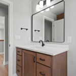 E1999 Hillside Main Bathroom. Thin Black Metal Framed Mirror. Stained Maple Vanity Cabinet with Golden Scribe Stone Countertops. Mannington Adura Flex "Basilica Pillar" Vinyl Tile Flooring.