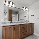 E1999 Hillside Owners Bathroom. Thin Black Metal Framed Mirrors. Stained Maple Vanity Cabinet with River Blue Leathered Granite Countertops. Mannington Adura Flex "Basilica Pillar" Vinyl Tile Flooring.