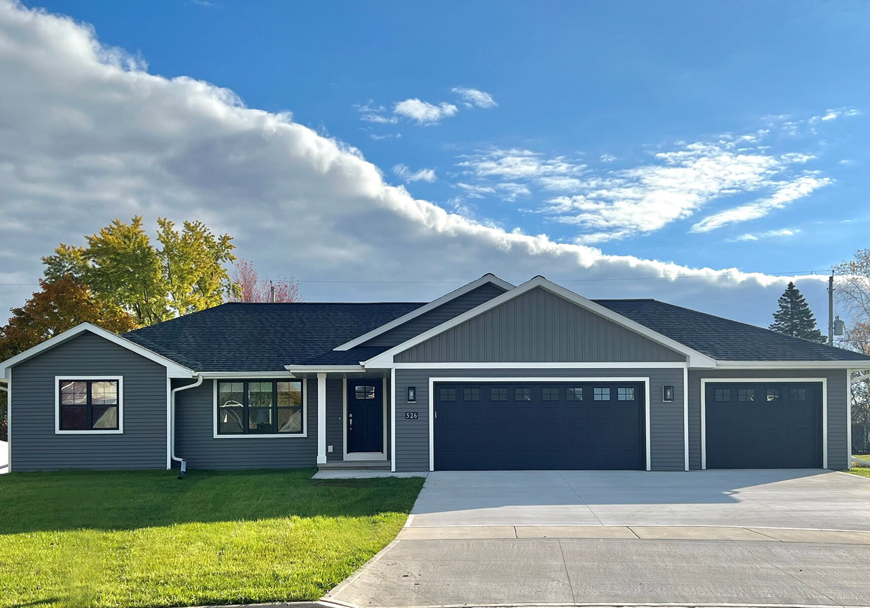 526 Rosemary Exterior. Black windows, black entry door, black overhead garage doors, white soffit/fascia, white exterior trim boards, Mitten "Yukon Gray" vinyl siding, CertainTeed Landmark "Moire Black" shingles.